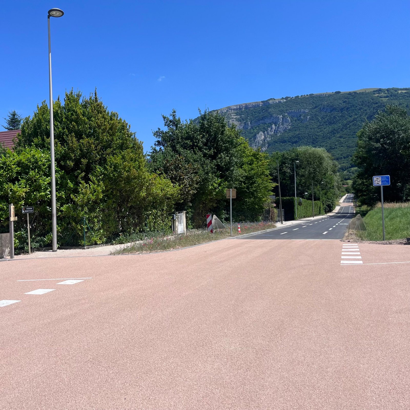 Carrefour habillé en résine gravillonnée rose corail, aménagement voirie communale en Savoie